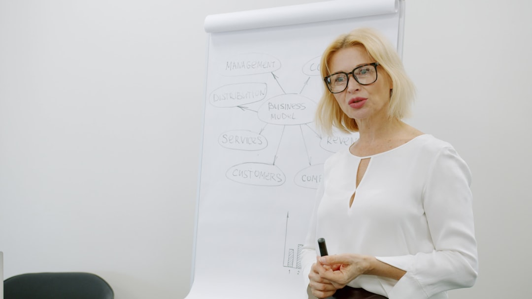 A professional woman presenting beside a board, illustrating posture and body language in an evaluative setting.